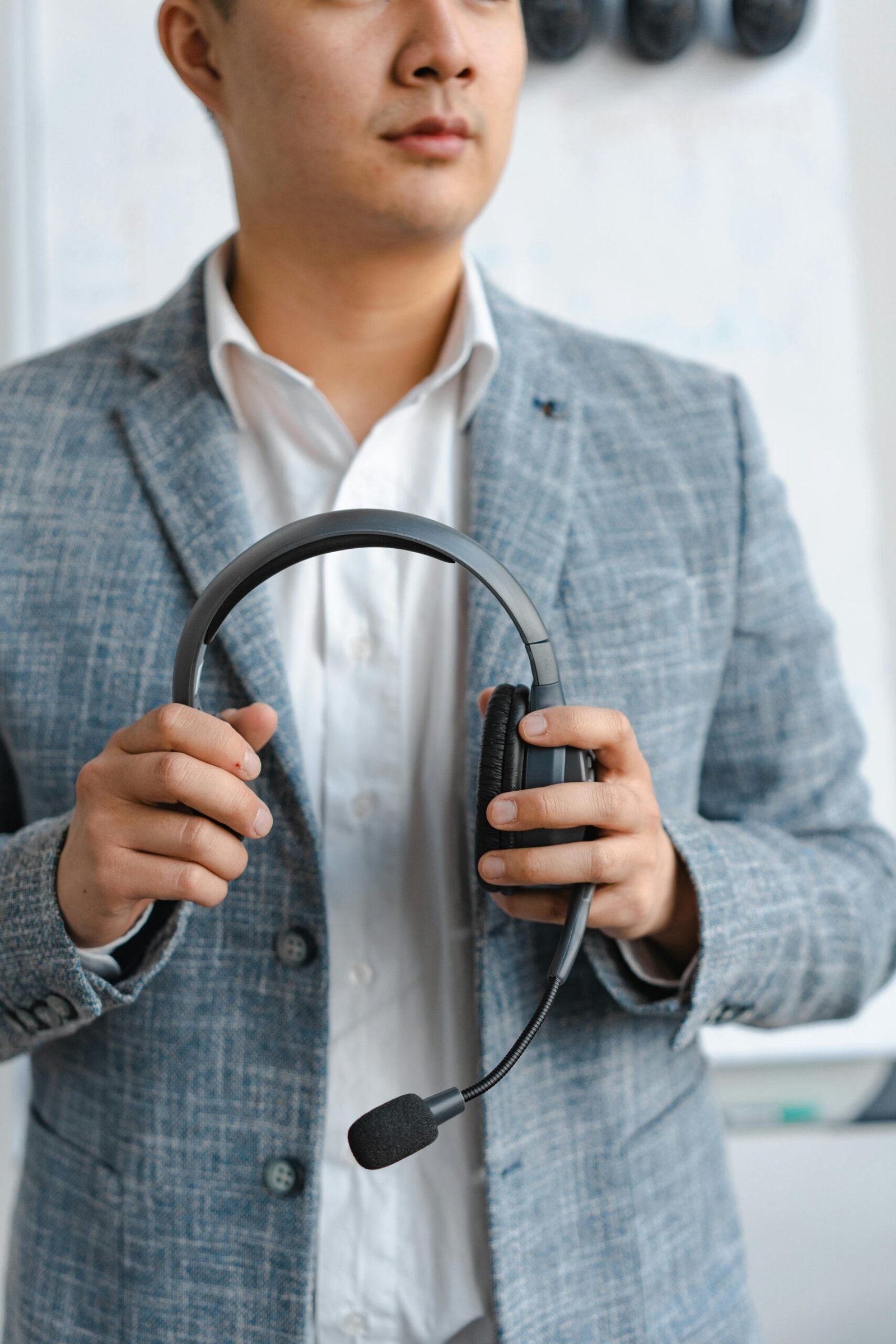 A call center agent in a gray suit holding a headset, portraying professionalism.